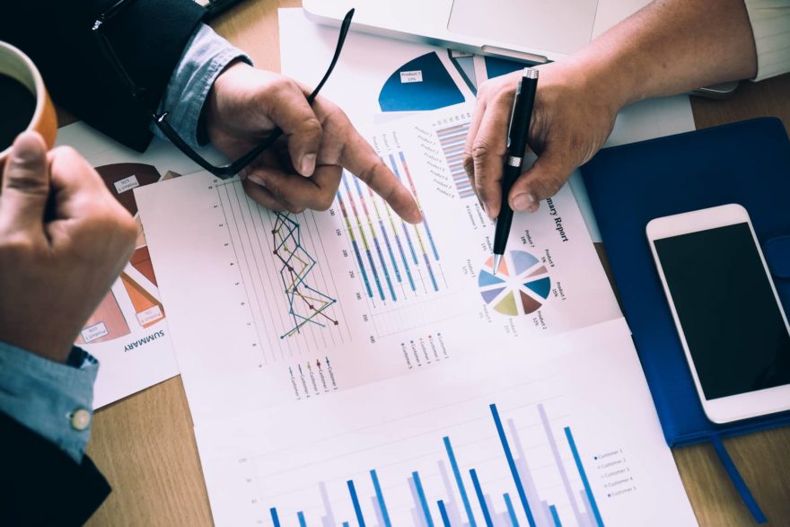 Business people brainstorming at office desk, they are analyzing financial reports and pointing out financial data on a sheet